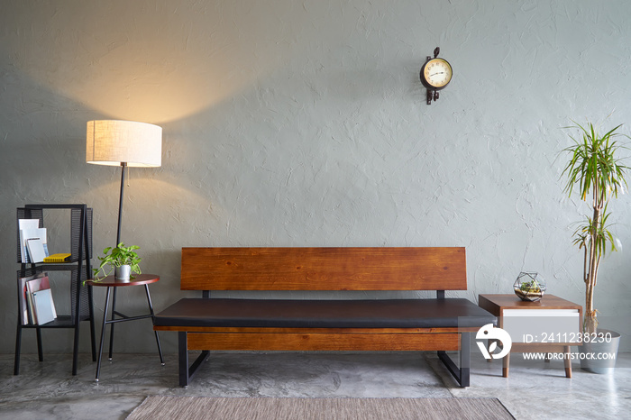 Modern living room with wooden bench sofa ,green plant , wooden tea table and clock. cement floor an