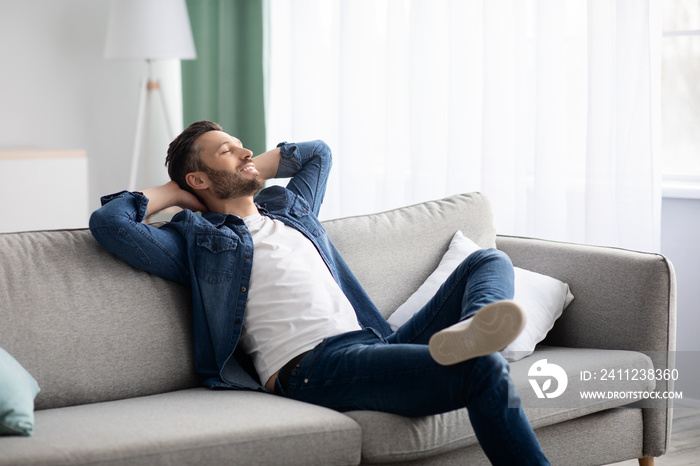 Happy bearded man relaxing on couch at home