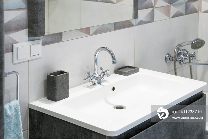 Modern bathroom interior with metal faucet and ceramic white sink. Bath accessories and mirror.