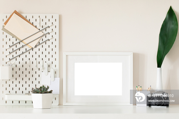 White home office desk with photo frame, supplies, flower. Minimal blank frame mockup design.