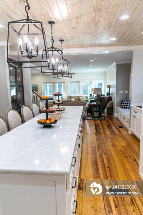 Large renovated white kitchen with textured subway tile, black iron lights and pine hardwood floorin