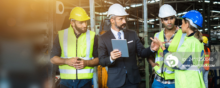 Industrial engineer and businessman in safety helmet working in factory, planning, discussing and training workers with tablet in metalwork place , teamwork and team concept