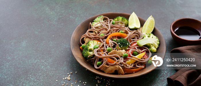 Stir fry noodles with chicken meat and vegetables in bowl on dark green background copy space