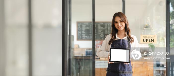 Young asia business owner woman with apron with open sign at café, open again, blank white screen tablet pc computer, looking to camera.