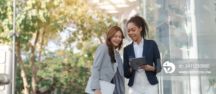 Two asia business women in conversation walking together on city street. Corporate colleagues workmate discussing new project while going to work. business outdoor.