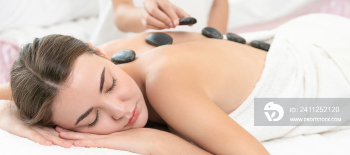 Hot stone massage treatment by therapist in spa.