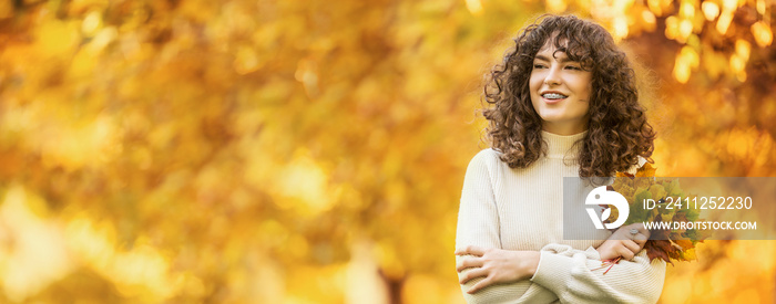 Young woman with autumn bouquet of maple leaves. Girl with a dental braces and curly hair