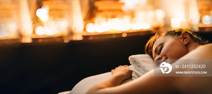 Woman having thai massage on bed with candles enjoying relaxing background