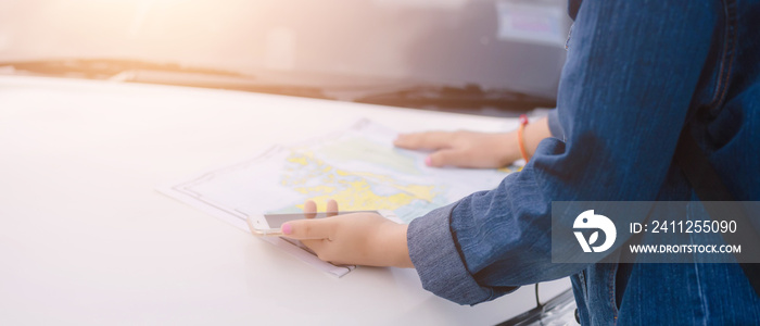 Asian woman using smartphone and map between driving car on road trip