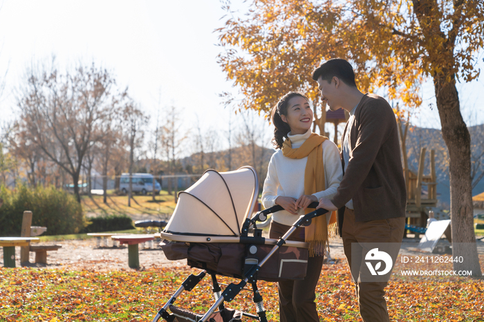 年轻夫妻推着婴儿车散步