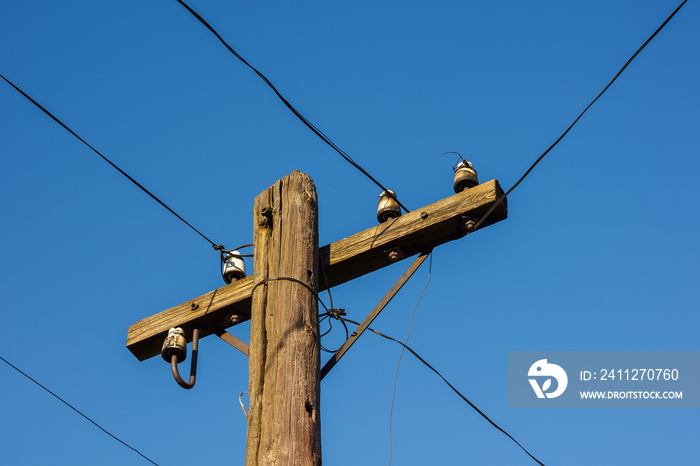 Old wooden telephone pole on a background of blue sky. The small depth of field