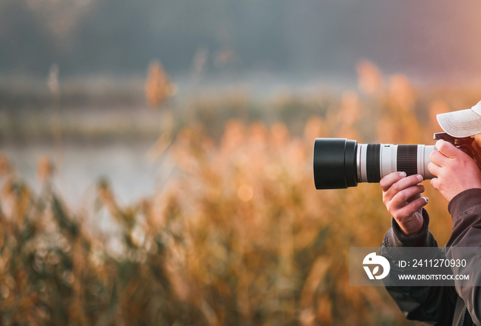 Professional wildlife photographer man taking pictures with digital camera equipment of birds and animals in nature.