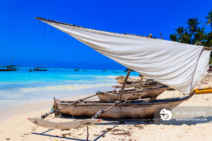 Traditional wooden dhow boats ashore on tropical sandy Nungwi beach in the Indian ocean on Zanzibar, Tanzania