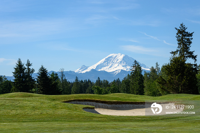 Beautiful day on a golf course, green fairway and bright sand trap with Mt Rainier in the background