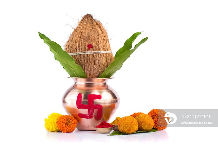 Copper Kalash with coconut, mango leaf, Haldi, kumkum and sweets with marigold flower decoration on a white background. Essential in Hindu puja.