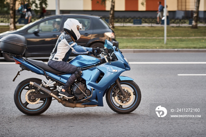 Motorcycle driver riding bike in the city street. Biker in helmet driving blue bike. Safety on the road