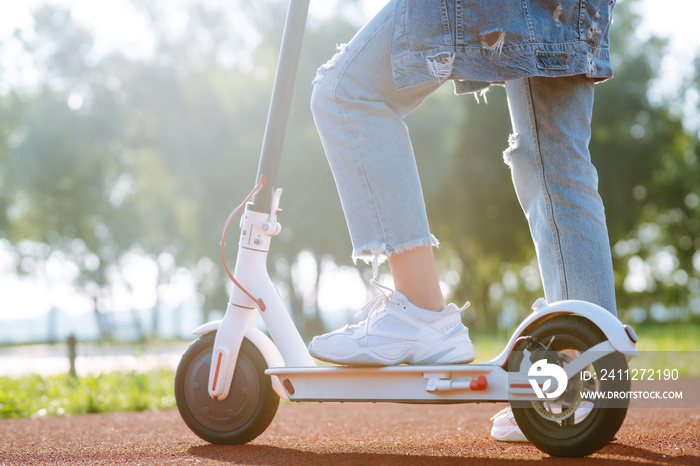 Legs of woman riding electric kick scooter. Ecological transportation concept.