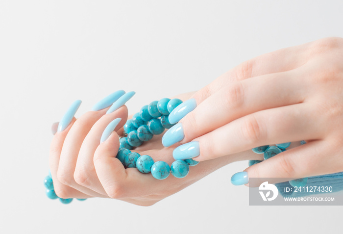 female hand  with manicure  and turquoise beads  on white  background