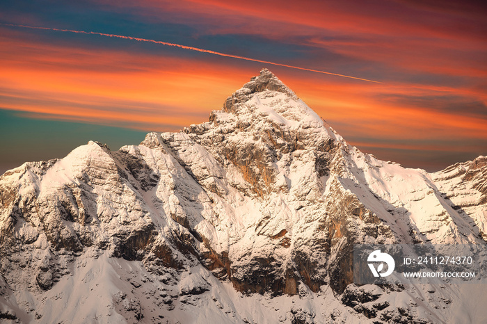 Dreamy winter landscape with snow covered mountains and a beautiful red orange sunset sunrise