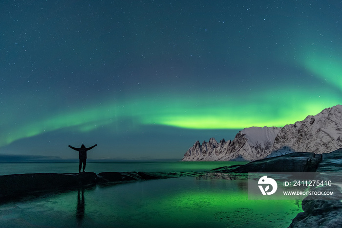 Man watching the northern lights, Aurora Borealis, Devil Teeth mountains in the background, Tungeneset, Senja, Norway