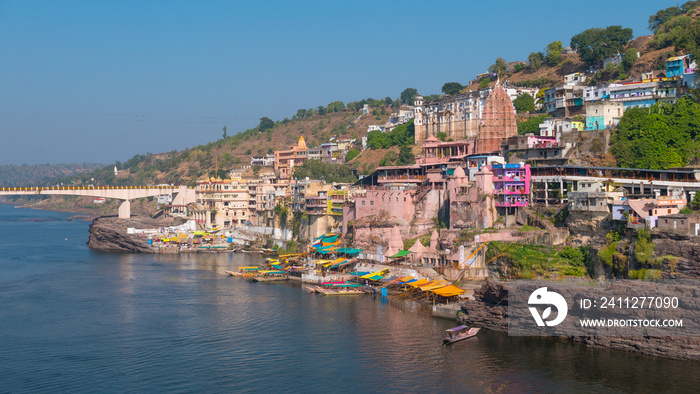 Omkareshwar cityscape, India, sacred hindu temple. Holy Narmada River, boats floating. Travel destination for tourists and pilgrims.