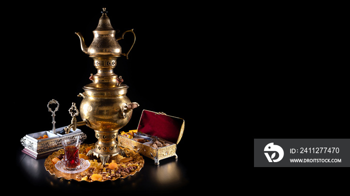 Oriental tea in a samovar, with sweets on a black background