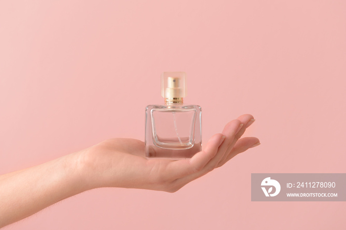 Woman holding bottle of perfume on color background