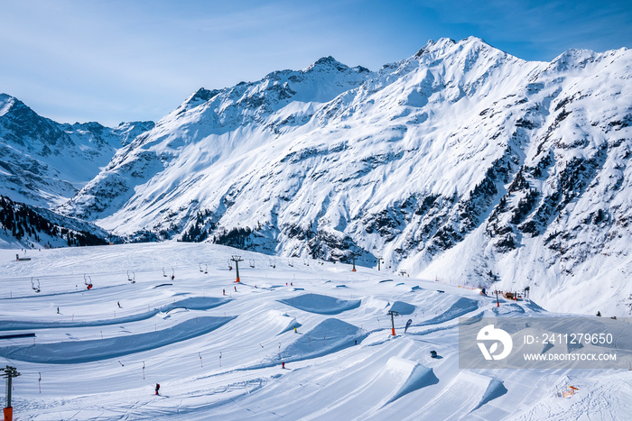 High angle view of skilift and snow park on snow covered landscape. Winter sports at beautiful white mountain range. Scenic view of alps against sky.