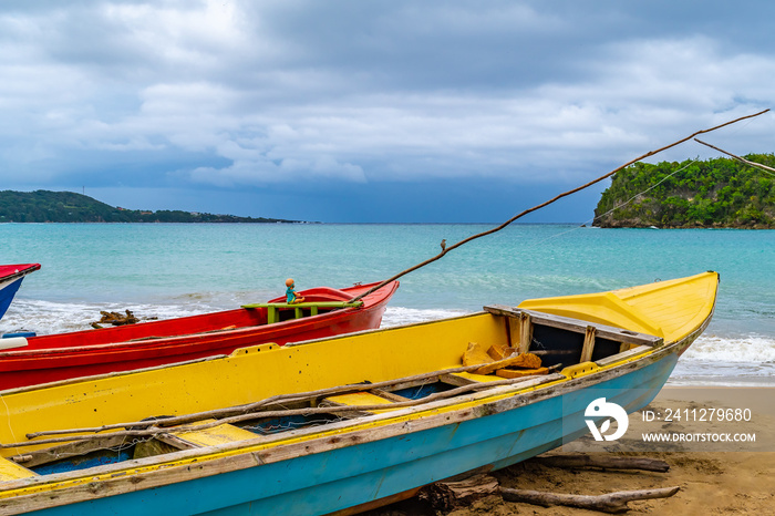 Colorful old wooden fishing boats docked by water on a beautiful beach coast land. White sand sea shore landscape on tropical Caribbean island. Holiday weekend summer vacation setting in Jamaica.