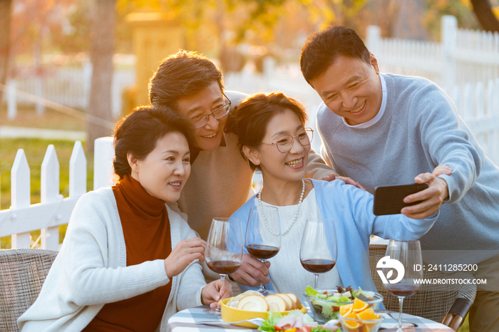 夕阳下中老年朋友在庭院里聚会喝酒拍照片