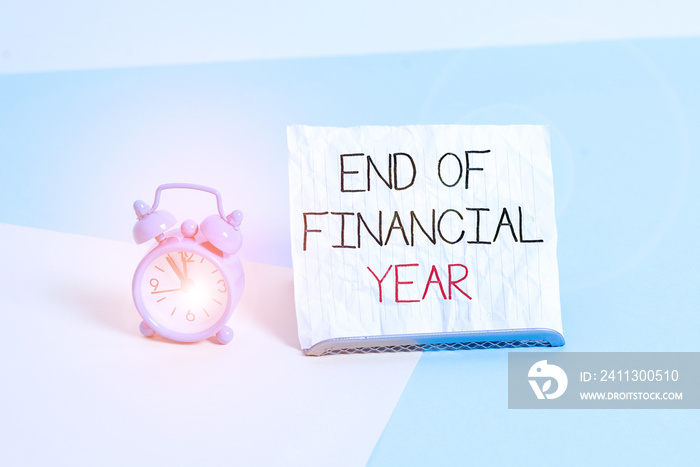 Conceptual hand writing showing End Of Financial Year. Concept meaning Revise and edit accounting sheets from previous year Alarm clock beside a Paper sheet placed on pastel backdrop