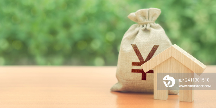 Wooden house figurine and Yen or yuan money bag. Budget, subsidized funds. Mortgage loan for purchase housing, construction or modernization. Tax, building maintenance. China, Japan