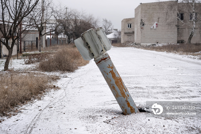 An unexploded Russian cruise missile sticks out of the asphalt in the middle of the street.