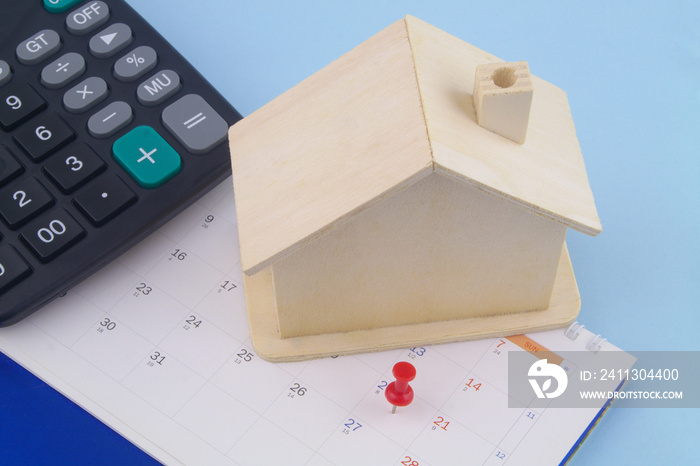 Wooden house and calculator on calendar. Best time for invest in real estate and house price concept.