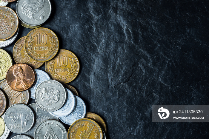 International coins background on black stone table top texture, with copy space