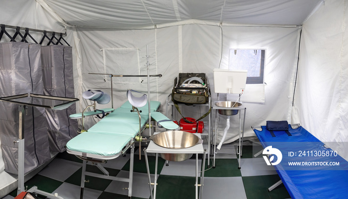 Tent operating room. Equipment for medical operating inside tent. Medical couches inside tent hospital. Location for operations. Rapidly erected hospital. Operating room of prefabricated room