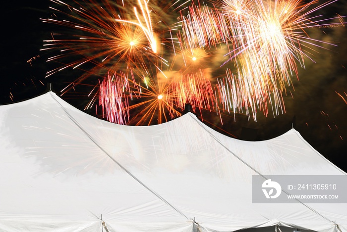 large marquee white events tent with fireworks lighting up the night sky behind