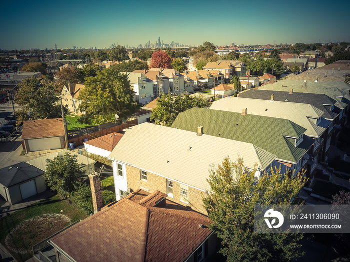 Vintage tone aerial view traditional residential neighborhood west of Chicago. Row of classic house with garden and detached garage. Skylines from downtown in background