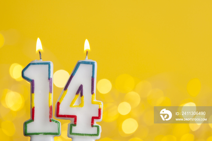 Number 14 birthday celebration candle against a bright lights and yellow background