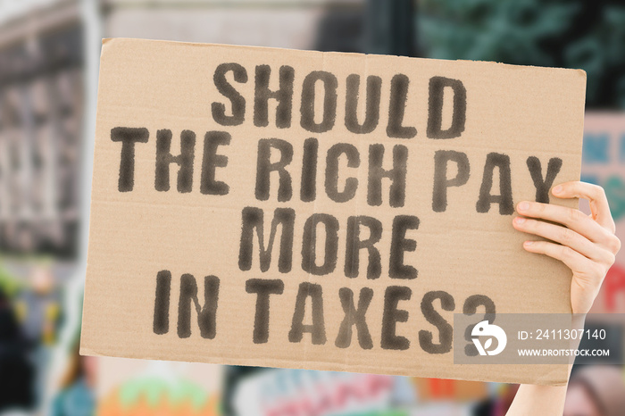 The question   Should the rich pay more in taxes?   on a banner in men’s hand. Human holds a cardboard with an inscription. Charges. Bill. Cuts. Government. Rule. Policy. Money. Business