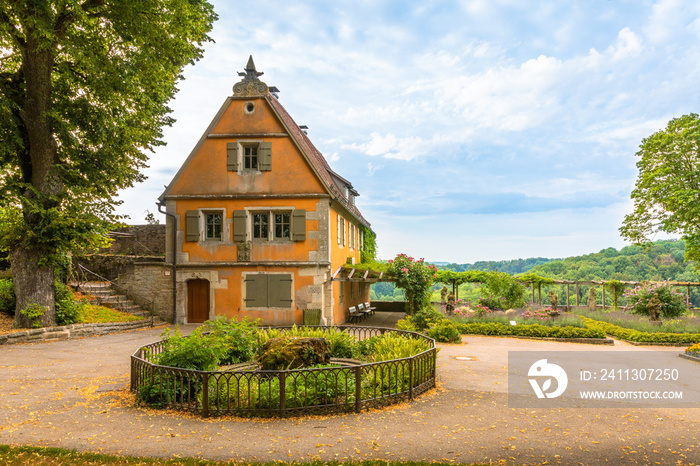 One painted timber frame house in a beautiful public garden, surrounded by trees and lawns, Rothenburg Ob Der Tauber, Germany.