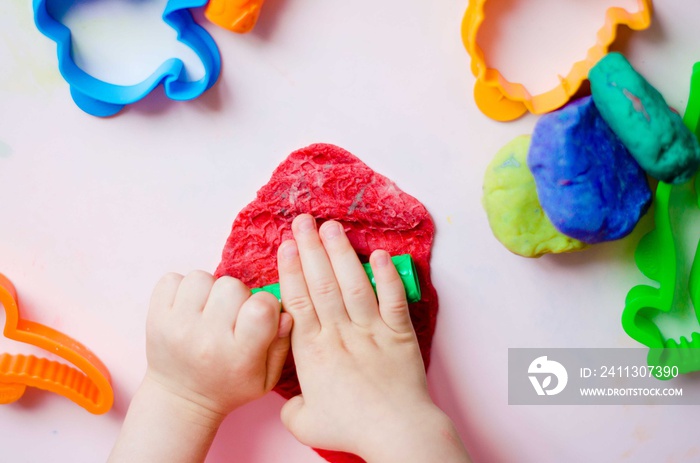 Child hands playing with colorful clay. Homemade plastiline