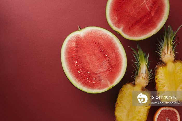 top view of cut watermelon and pineapple on red surface