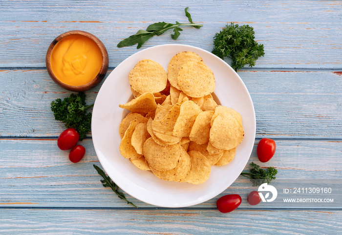 Crispy Nacho With Spicy Cheese dip in a white plate. Traditional fast food on wooden background top view