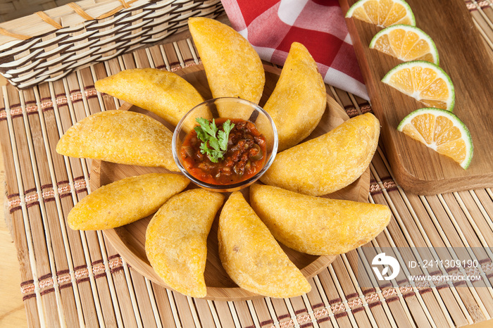 Tasty colombian food, fried empanada; photo on wooden background.