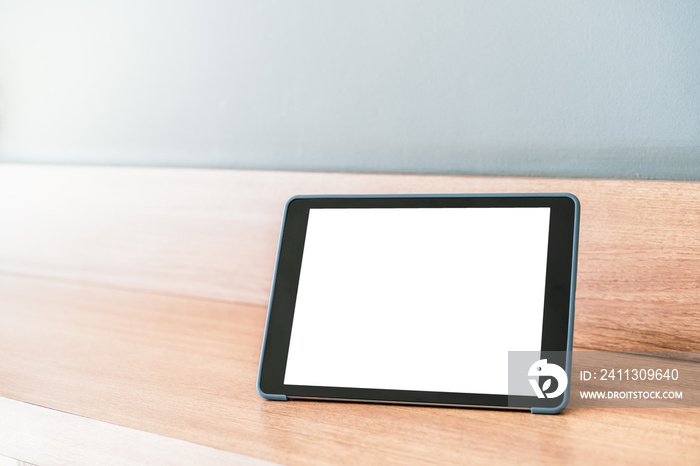 The mockup tablet stands on the wooden desk in the corner of the office background with natural light