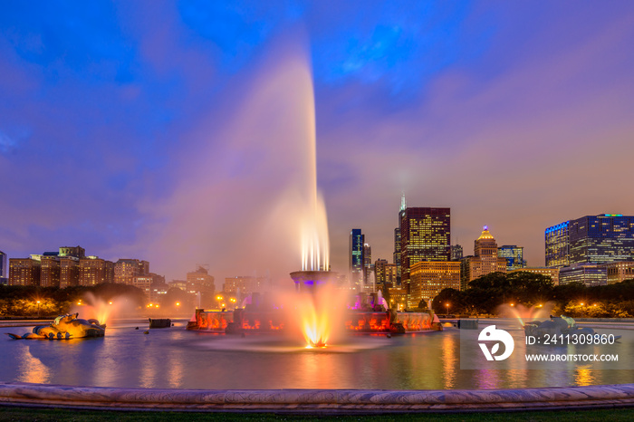 Chicago skyline panorama with skyscrapers and Buckingham fountain in Grant Park at night lit by colorful lights.