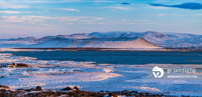 Huge panorama of volcano crater over the lake covered by snow