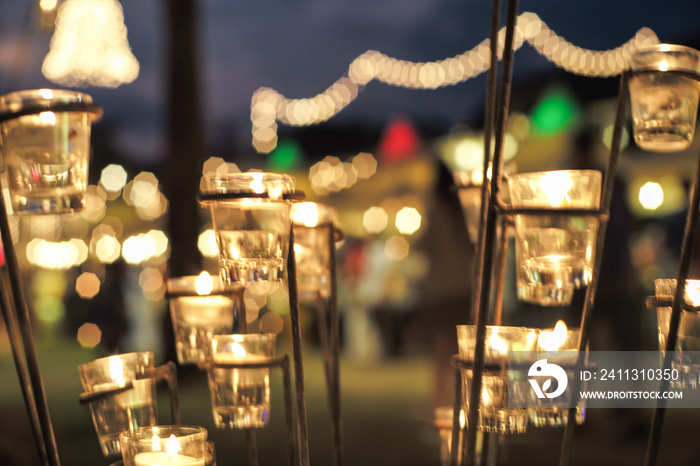 Selective focus on candles in small glasses with blurred bokeh lights in background