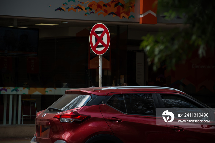 Red vehicle committing an infraction and parked in the no parking and stop zone.